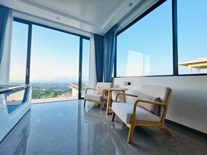 Ein modernes Zimmer mit großen Fenstern, einem Balkon und Blick auf die Stadtlandschaft.