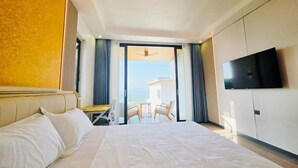 Een hotelkamer met een groot bed, een aan de muur bevestigde televisie en een balkon met uitzicht.