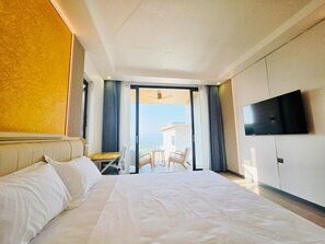 Ein Hotelzimmer mit einem großen Bett, einem an der Wand befestigten Fernseher und einem Balkon mit Blick.