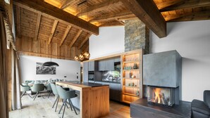 Una cucina moderna con isola centrale, mobili a incasso, una parete decorata in pietra e un camino.