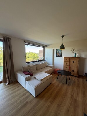 A modern living room with a sectional sofa, a wooden cabinet, and a dining table. - Slow Down Together – A Cozy Apartment in Monschau for 2 (up to 4) (Monschau)