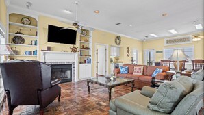 Una sala de estar con chimenea, televisor y estantería.