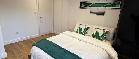 A bedroom with a bed, a door, a wall-mounted artwork, and a wardrobe.