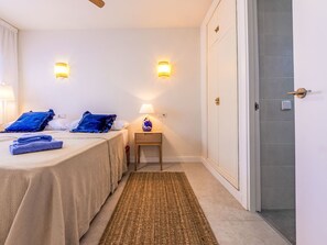 A hotel room with two beds, a nightstand with a lamp, a wall-mounted light, and a door with a handle. - Marinada Cambrils by Interhome (Cambrils)