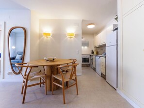 A modern kitchen with white cabinets, a round wooden table, and two wall-mounted lights. - Marinada Cambrils by Interhome (Cambrils)