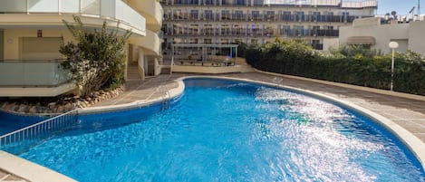 Una piscina rodeada por un edificio de varios pisos con balcones.