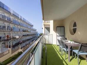 A balcony with a view of a cruise ship, a dining table with chairs, and a small garden area. - Calafont by Interhome (Salou)