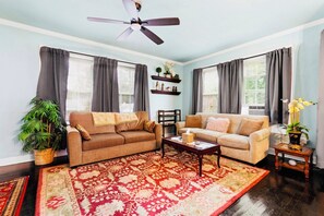 A living room with two sofas, a coffee table, a ceiling fan, and a large window with curtains. - Charming 2-bedroom Apt close to Downtown San Antonio (San Antonio)