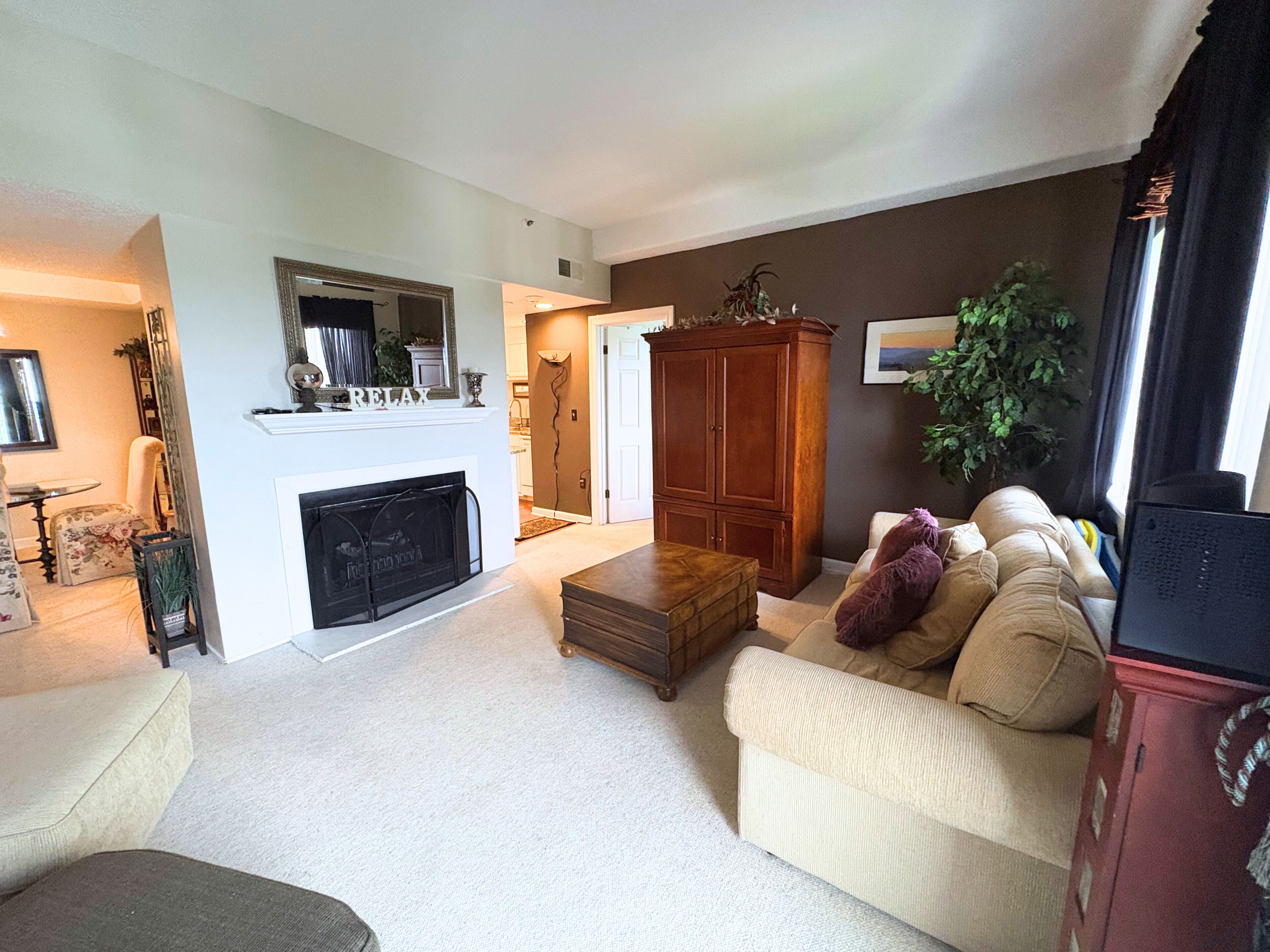 A living room with a fireplace, a sofa, a wooden cabinet, and a television.