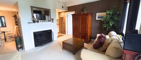 A living room with a fireplace, a sofa, a wooden cabinet, and a television.