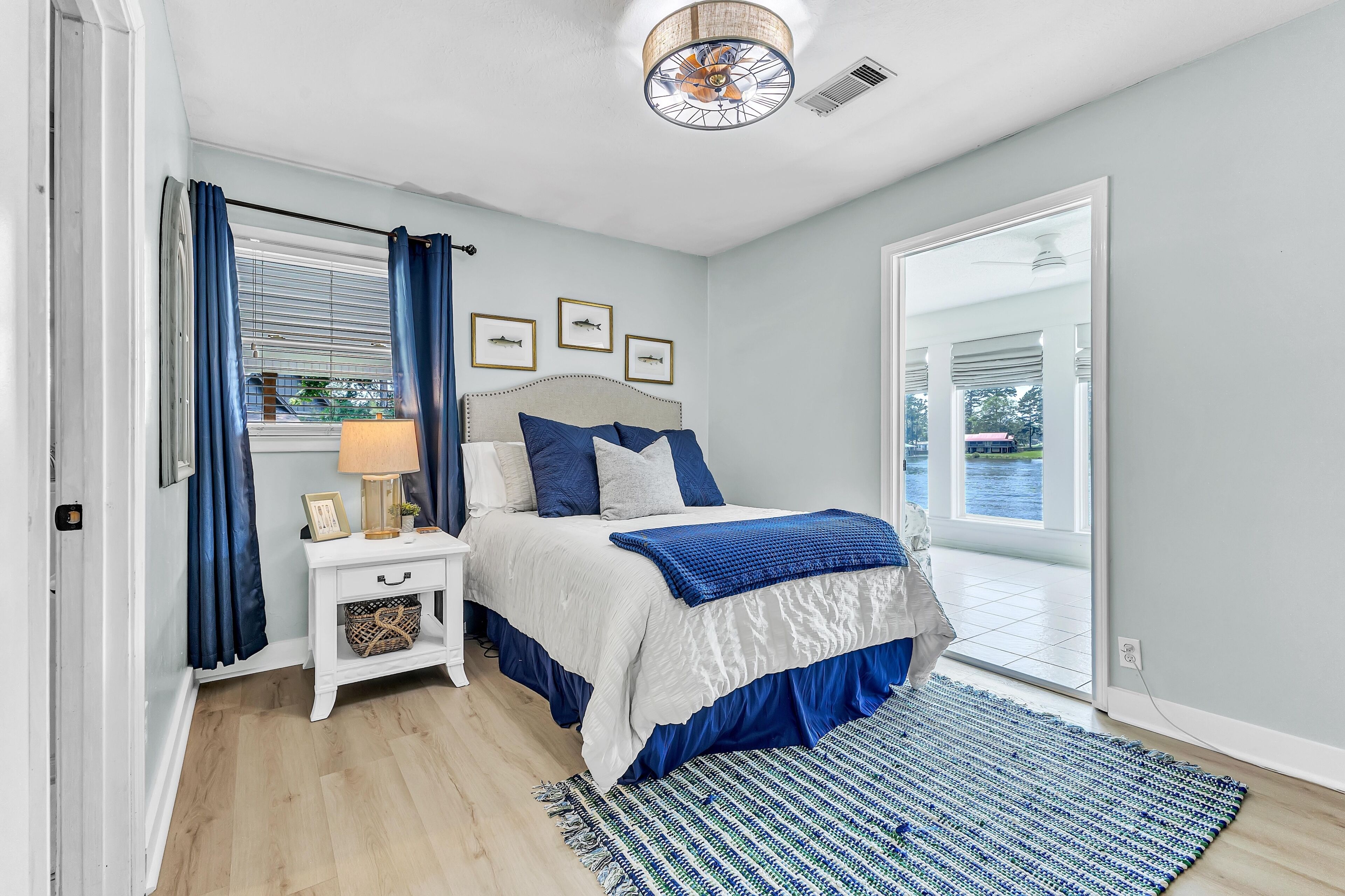 A bedroom with a bed, nightstand, and a view through a glass door.