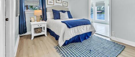 A bedroom with a bed, nightstand, and a view through a glass door.