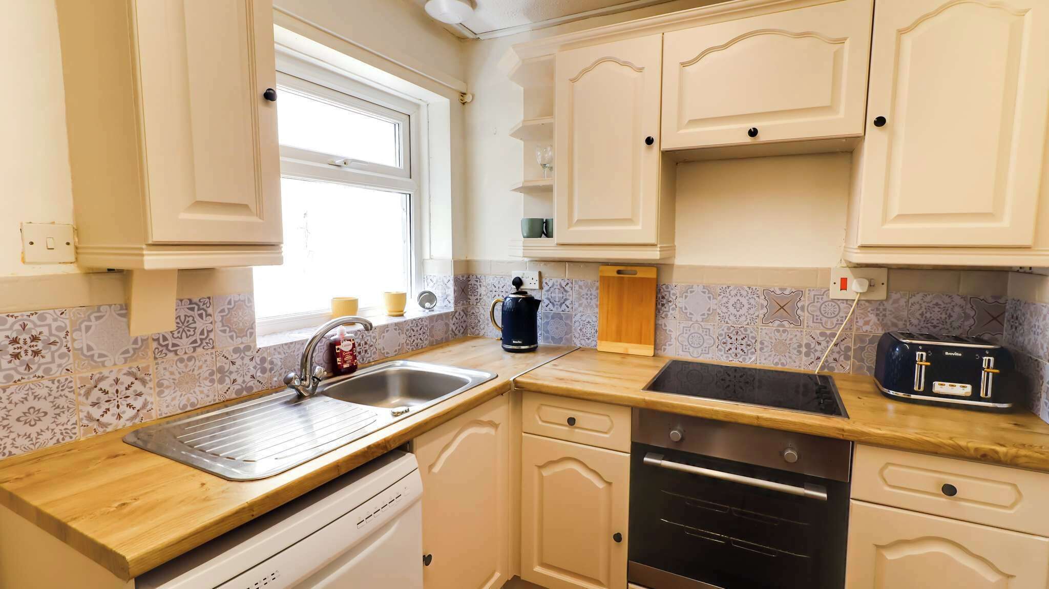 A kitchen with a sink, stove, and toaster.