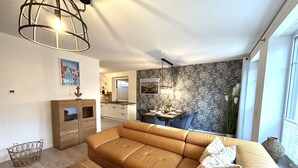 Un saló modern amb un sofà, una taula de centre de fusta i una zona de menjador amb taula i cadires.