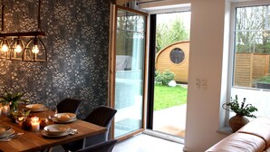 Zona de menjador amb taula preparada per a dinar, un sofà i vista a l'exterior.
