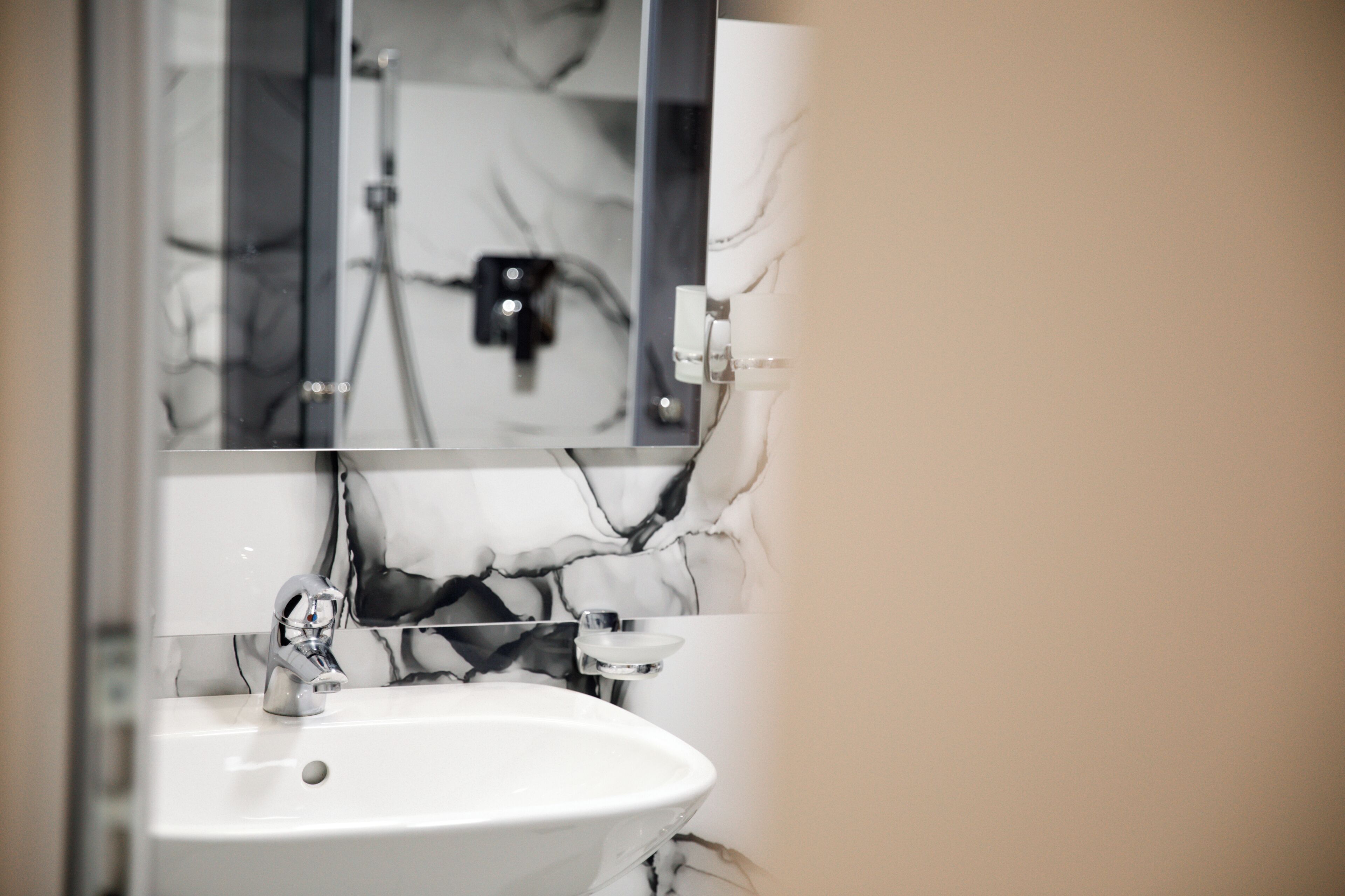 A bathroom with a white sink, a mirror, and a marble backsplash.