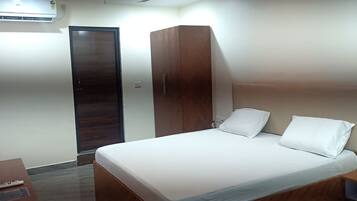 Un dormitorio con cama, armario, puerta y una mesita.