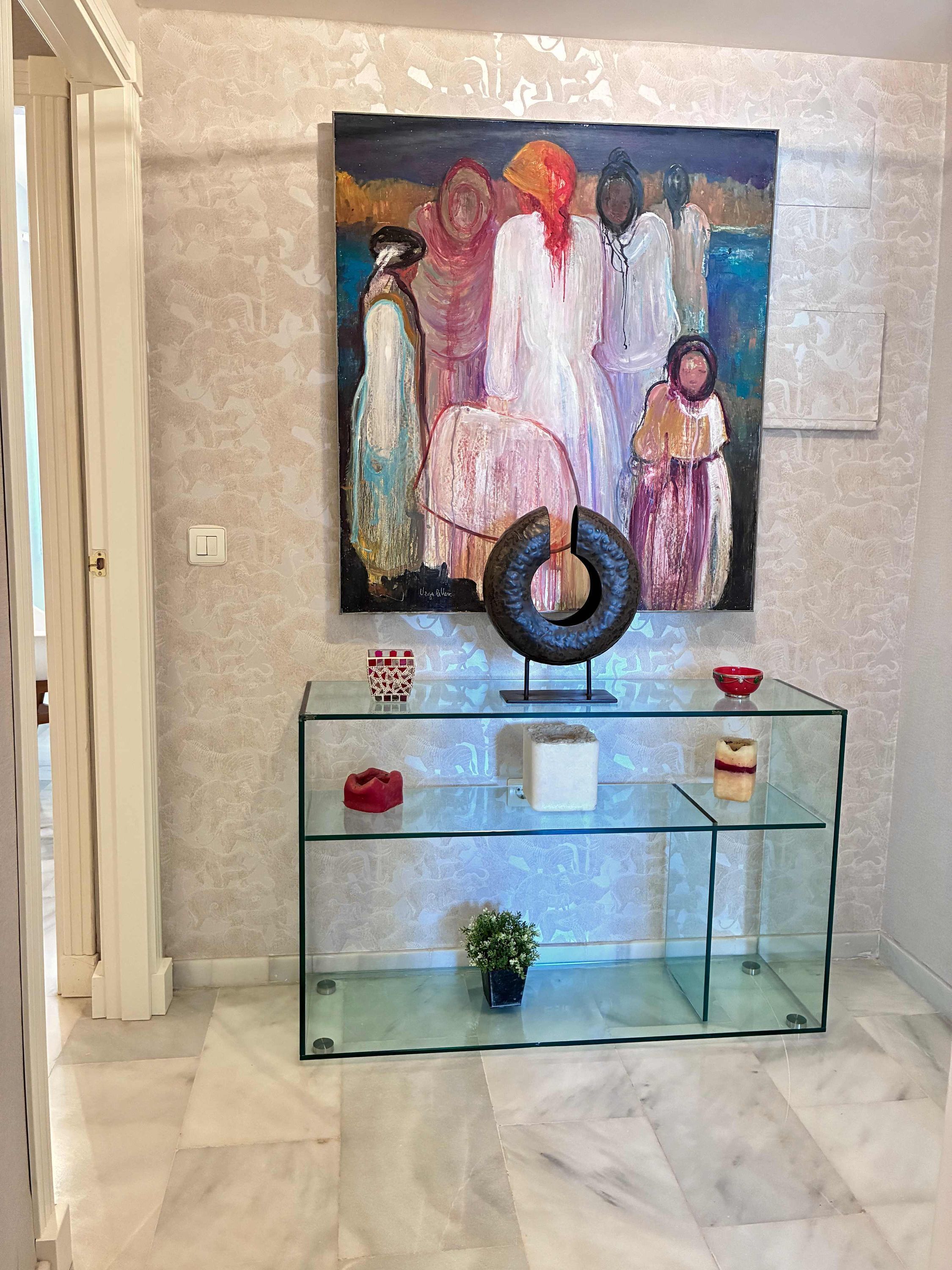 A hallway with a glass display cabinet, a painting on the wall, and a door.