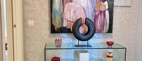 A hallway with a glass display cabinet, a painting on the wall, and a door.