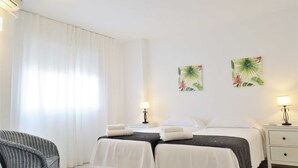 Camera d'albergo con due letti, una sedia, un comodino e decorazioni a parete.