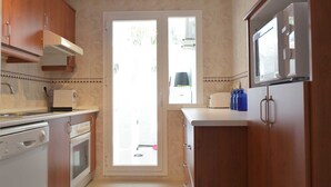 Una cucina con mobili in legno, forno a incasso, microonde e una finestra.