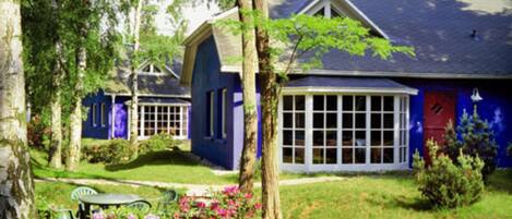 A house with a large window, a door, and a small garden with flowers.