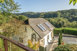 Una casa amb teulada inclinada, panells solars i vista a una vall boscosa.