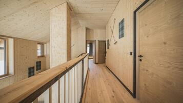 A wooden interior with a long hallway, wooden walls, and a wooden railing.