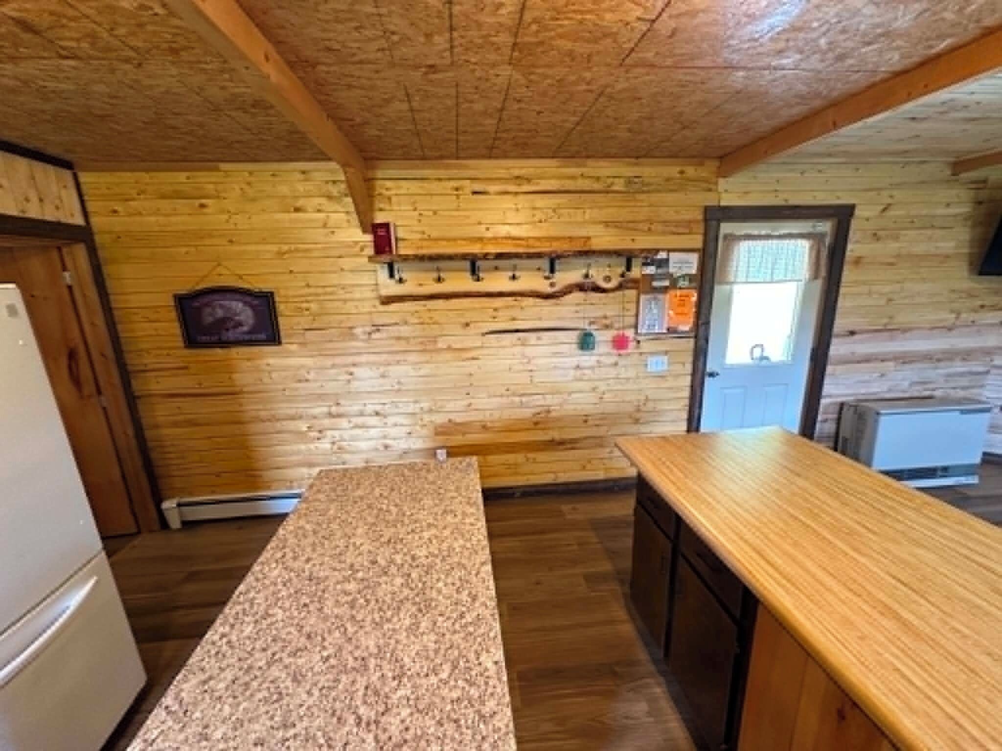 Une cuisine avec des murs en bois, un plan de travail en granit et un étagère suspendue pour ranger les ustensiles.
