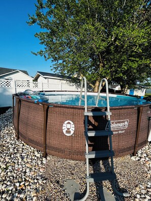 A Coleman in-ground pool with a ladder, surrounded by pebbles, under a tree. -  3-bedroom house with above ground pool  in a quiet neighborhood in Little River (Little River)