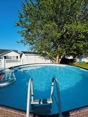 A swimming pool with a ladder, surrounded by a white fence, and a tree in the background. -  3-bedroom house with above ground pool  in a quiet neighborhood in Little River (Little River)