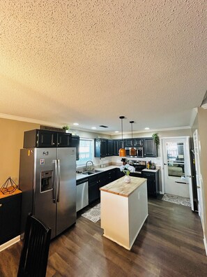 A modern kitchen with a central island, built-in appliances, and dark cabinetry. -  3-bedroom house with above ground pool  in a quiet neighborhood in Little River (Little River)