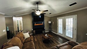 Ein Wohnzimmer mit Deckenventilator, Kamin, Sofa und einer Tür mit Fenster.