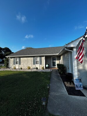 A residential house with a stone facade, a front porch, and an American flag. -  3-bedroom house with above ground pool  in a quiet neighborhood in Little River (Little River)