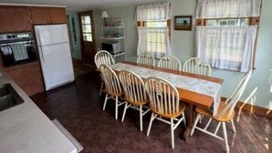 A compact kitchen with a refrigerator, stove, and sink. There is a dining area with a table and chairs.