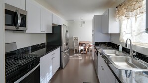 Una cucina moderna con elettrodomestici in acciaio inossidabile, mobili bianchi e un piano di lavoro in marmo.