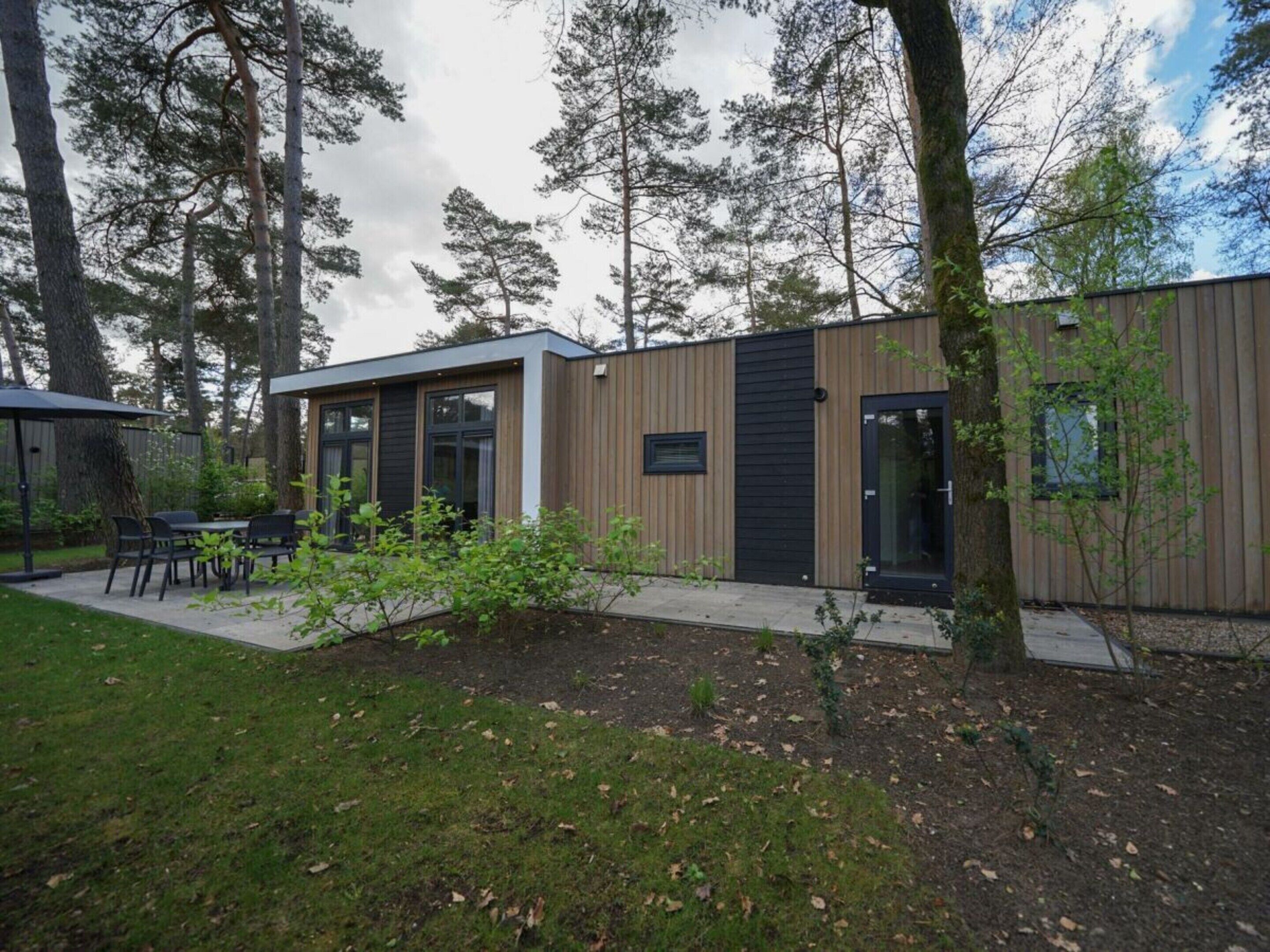 A modern building with a patio area, a dining table, and chairs.