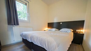 A bedroom with a large bed, bedside tables, a window with curtains, and a radiator. - Holiday Home in Otterlo With Terrace (Otterlo)