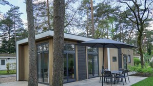 A modern house with a patio, large windows, and a dining area with chairs and an umbrella. - Holiday Home in Otterlo With Terrace (Otterlo)
