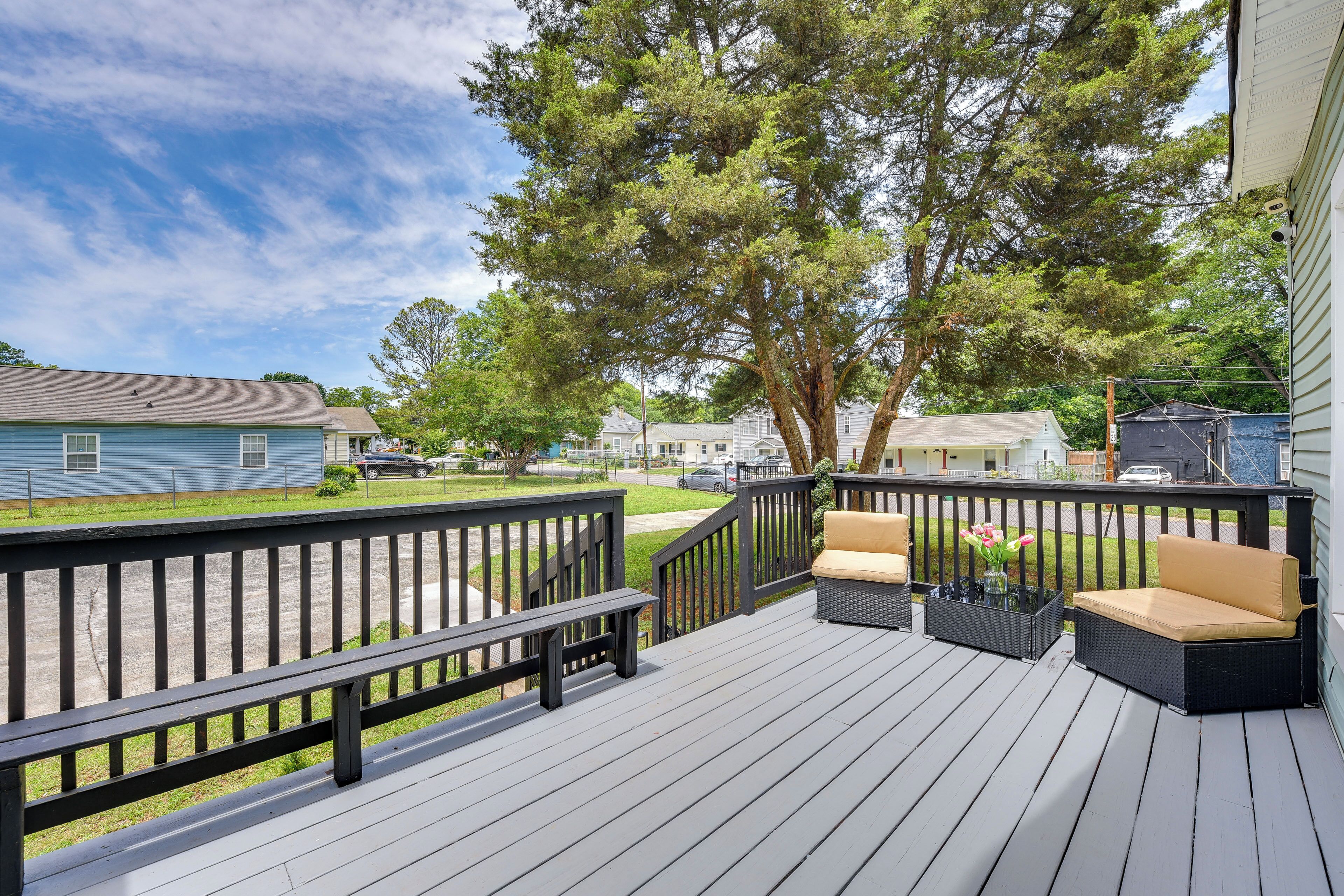 A deck with outdoor furniture, a bench, and a tree.