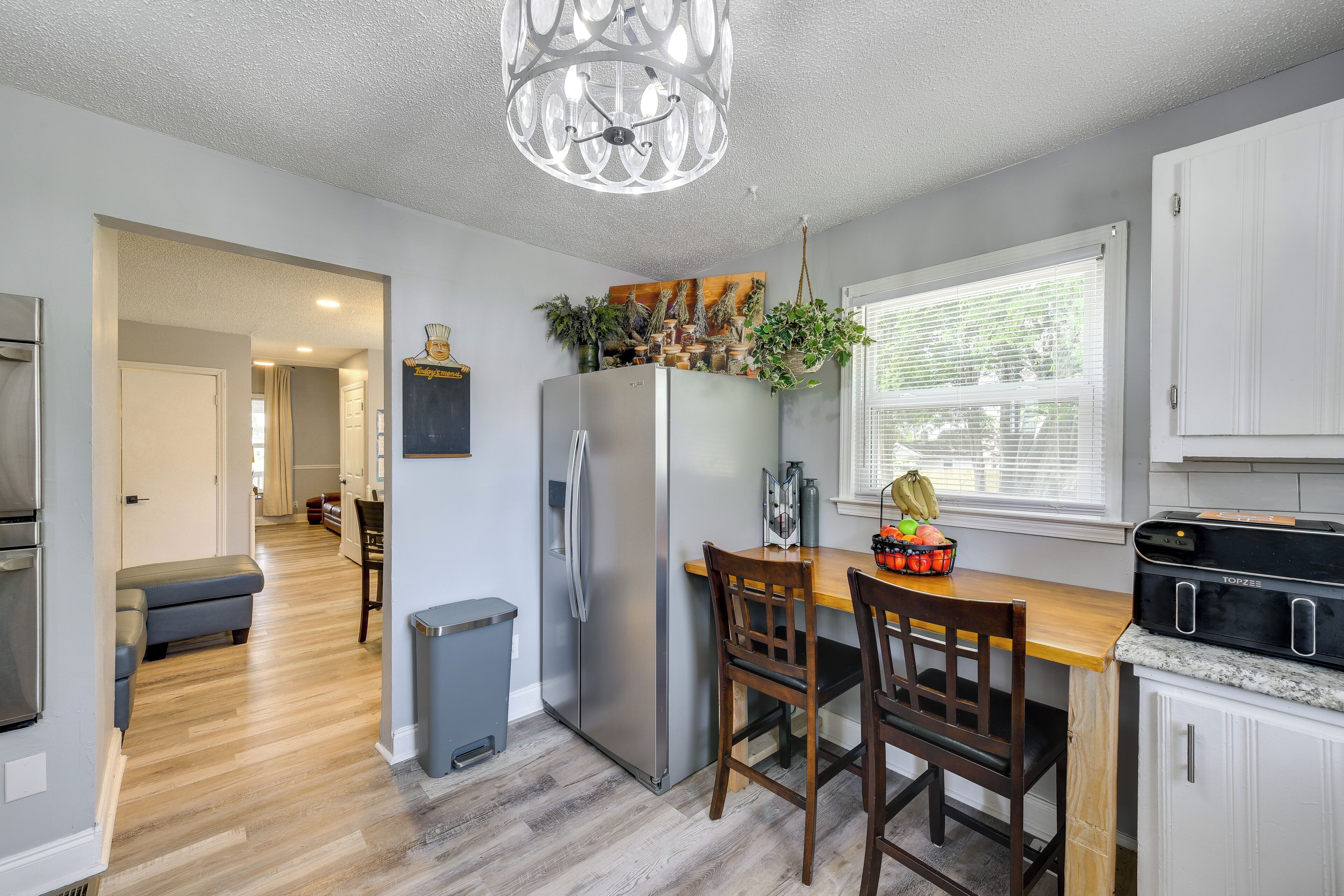 A modern kitchen with a stainless steel refrigerator, wooden dining table, and chairs.