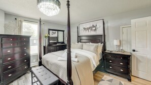 A four-poster bed with a canopy, dark wooden dresser, bedside tables, and a chandelier. - Skyline Views + Outdoor Fun: Charlotte Escape! (Charlotte)