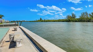 A waterfront promenade with a concrete walkway, benches, and a view of the water. - Steps to Beach! Charming Indian Shores Condo (Indian Shores)