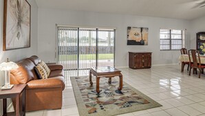 Amplia sala de estar con un sofá de cuero, una mesa de centro de madera y una zona de comedor con sillas y una mesa.