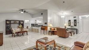 Amplia sala de estar con comedor, sofá, mesa de centro y ventilador de techo.