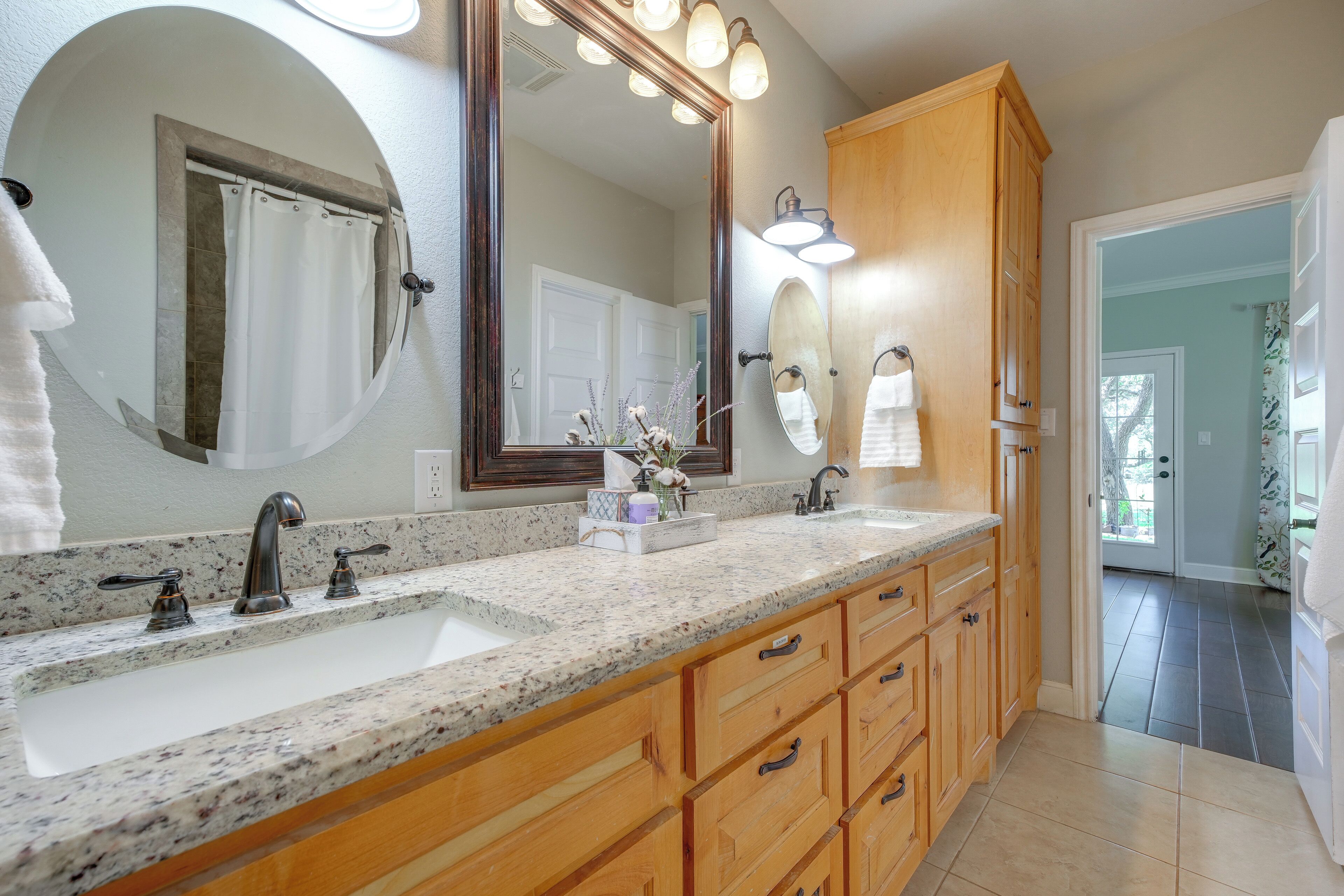 Une salle de bain avec deux lavabos, un grand miroir, des meubles en bois et un espace douche.
