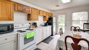 A kitchen with wooden cabinets, a refrigerator, a microwave, an oven, and a dining table with chairs. - 3 Mi to Fort Sill! Family Retreat w/ Fenced Yard (Lawton)
