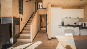 Moderni keittiö, jossa on puiset kaapit, sisäänrakennettu liesi sekä ruokailutila, jossa on pöytä ja tuolit.