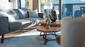 Una sala de estar moderna con un sofá gris, una mesa de centro de madera y un ventanal grande.