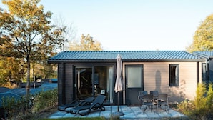 Una casa moderna con patio, mobiliario exterior y un espacio cubierto.